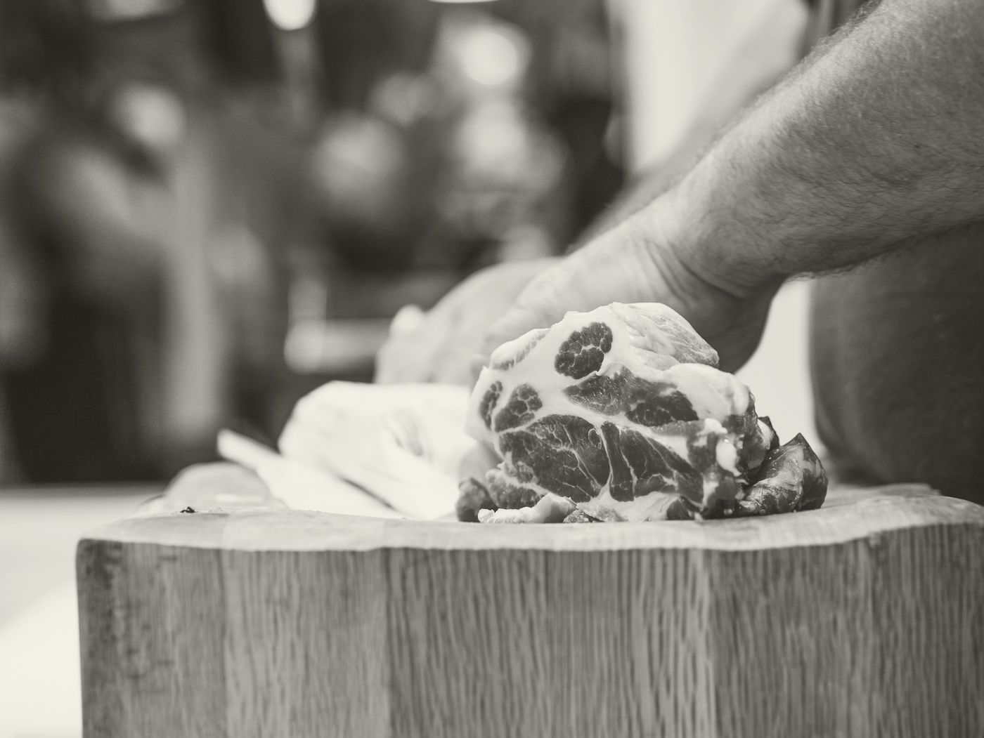 Una mano che appoggia un pezzo di carne sul ceppo di legno